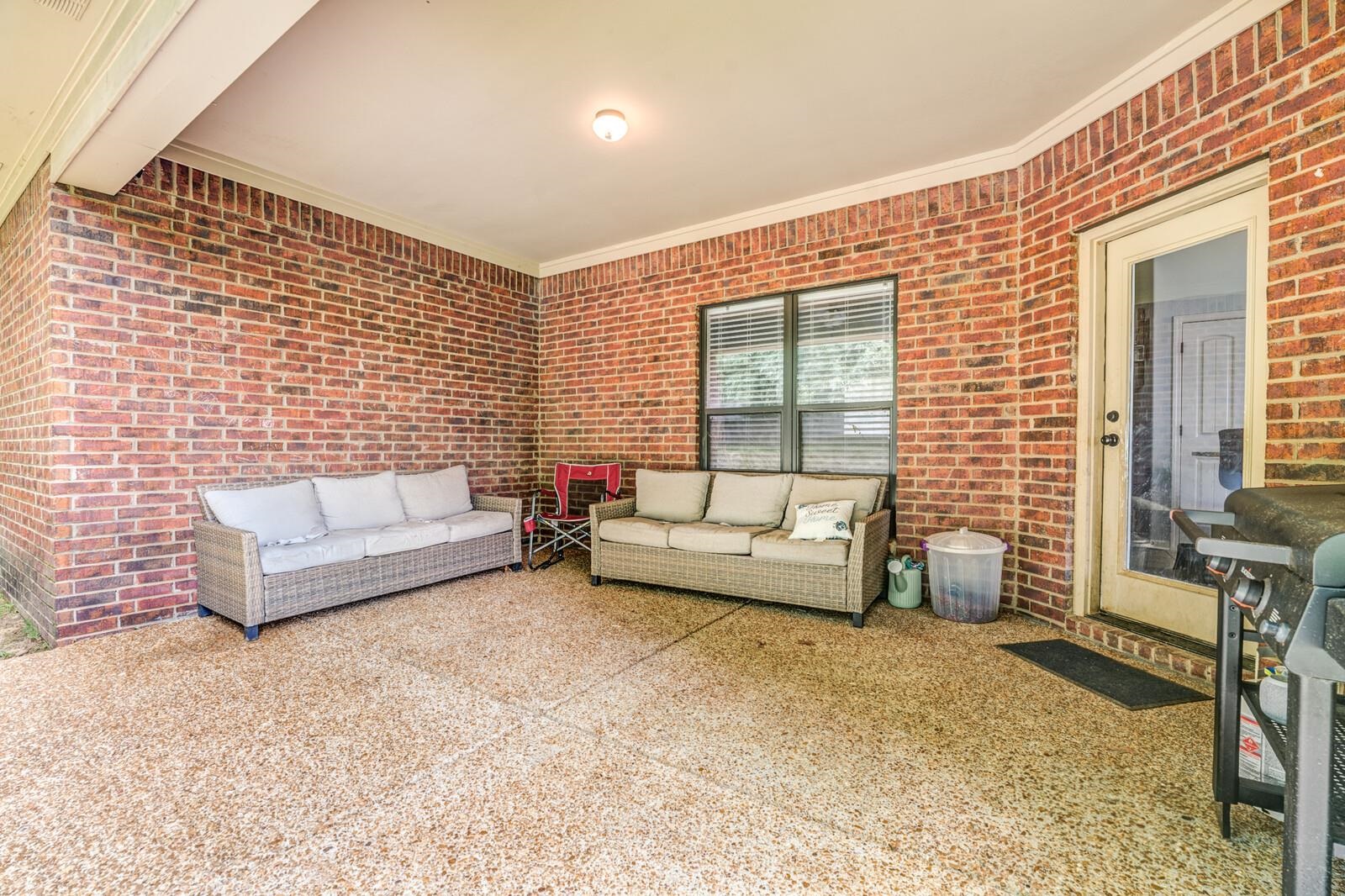 4671 Hampton Ridge Lane Bartlett, TN 38002 - Photo 33 of 40 Covered patio featuring brick walls, an exposed aggregate concrete floor, a ceiling-mounted light fixture, and a glass-paneled exterior door