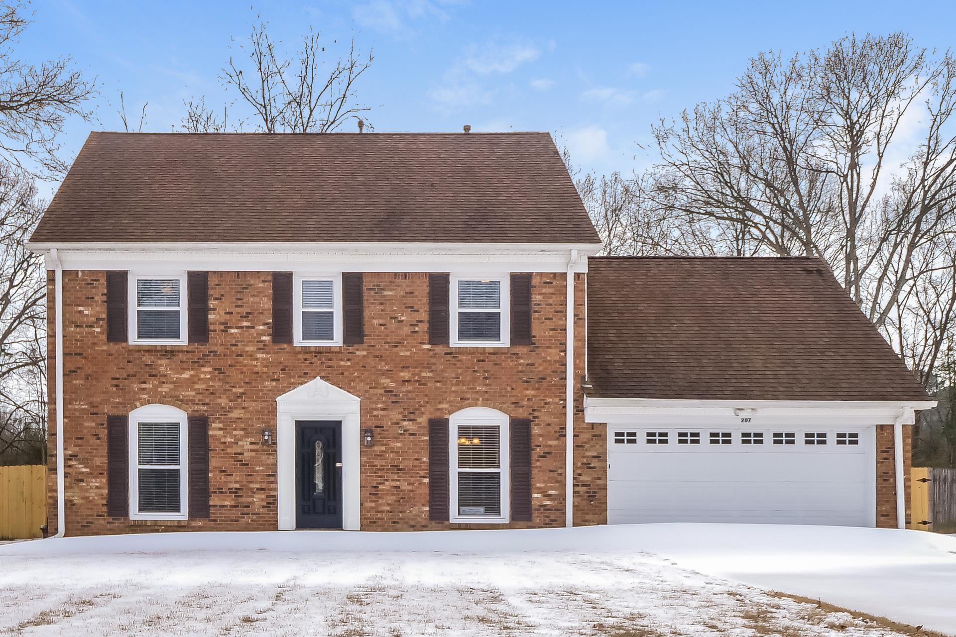 Colonial-style house with brick siding, roof with shingles, and an attached garage