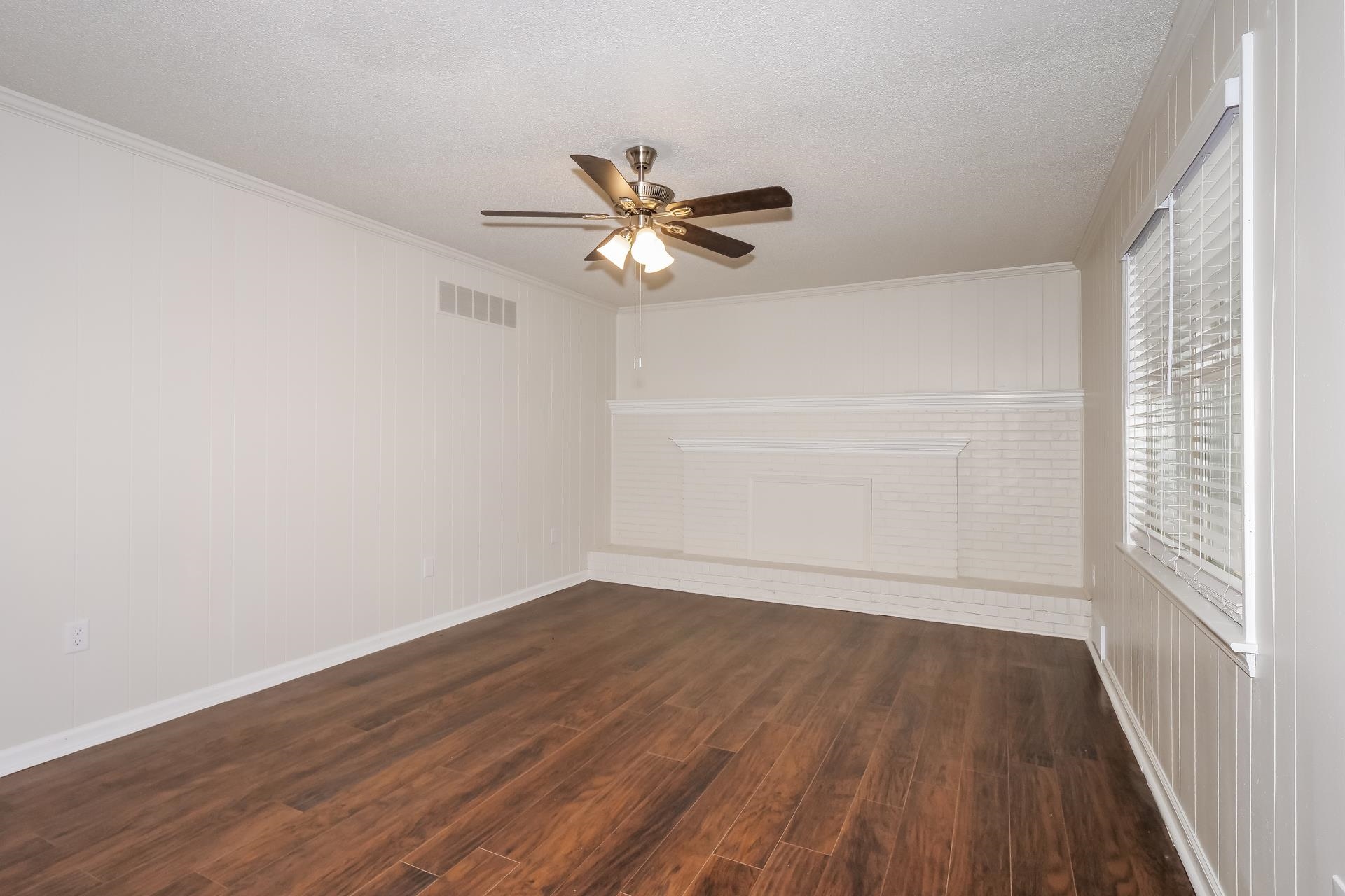 207 East Pecan Valley Street Collierville, TN 38017 - Photo 13 of 18 Empty room featuring dark wood-type flooring, wood walls, ceiling fan, ornamental molding, and a textured ceiling