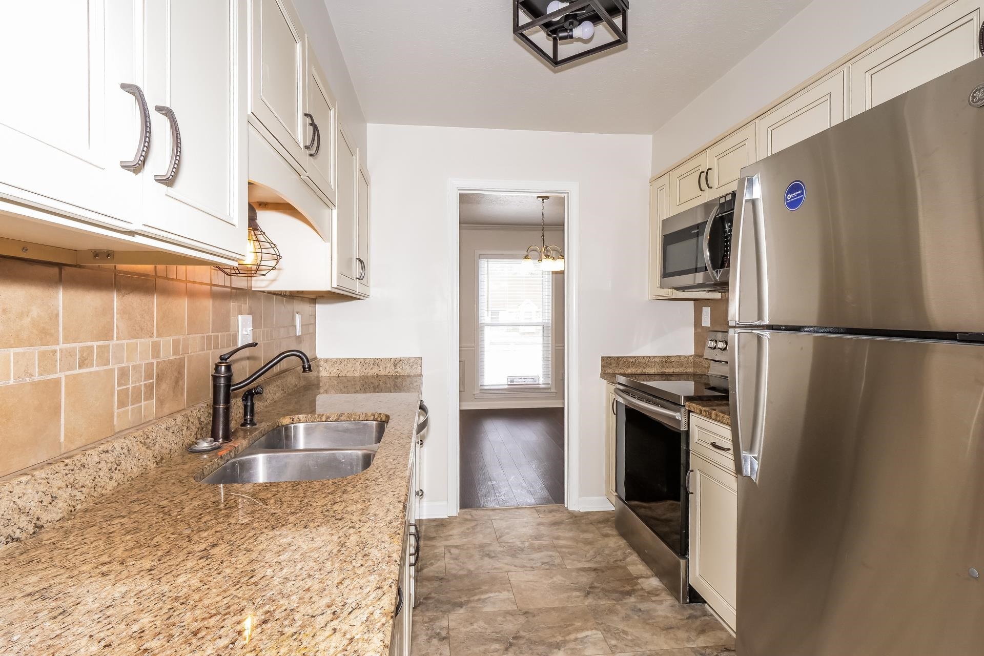 207 East Pecan Valley Street Collierville, TN 38017 - Photo 16 of 18 Kitchen featuring stainless steel appliances, dark stone counters, decorative light fixtures, and tasteful backsplash