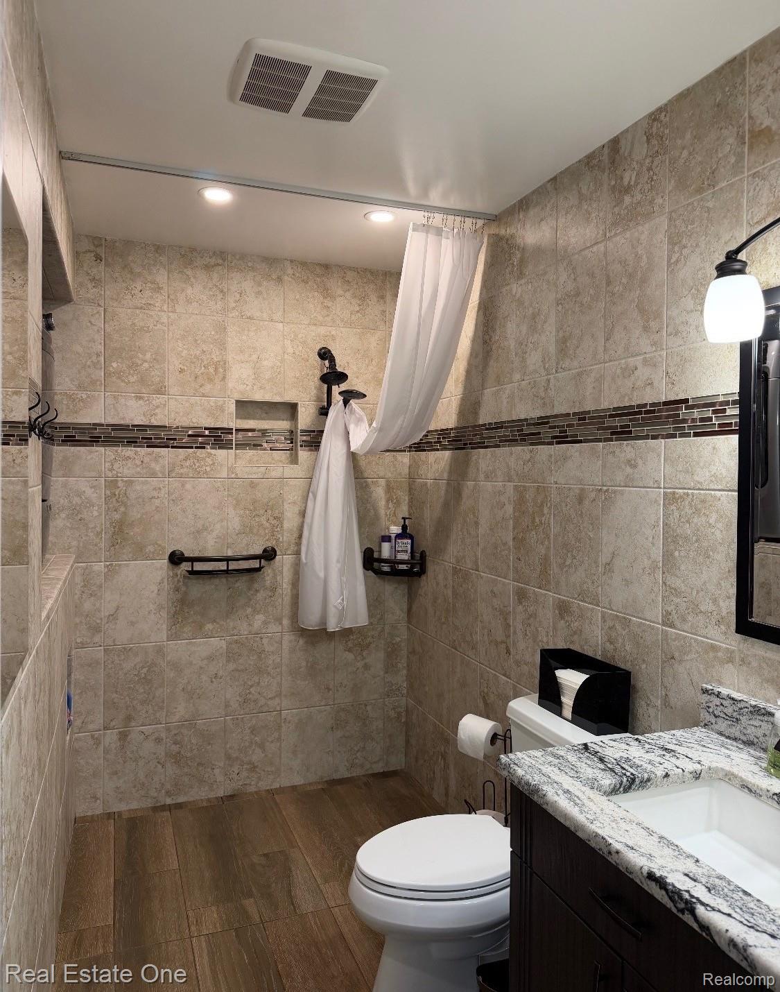 1115 Torpey Road Troy, MI 48083 - Photo 32 of 38 Bathroom featuring wood-finish flooring, tiled shower walls with a mosaic accent band, a built-in shower niche, and recessed lighting