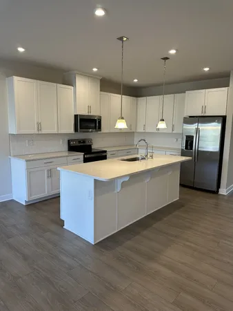 a large kitchen with stainless steel appliances kitchen island a large counter top and wooden floors