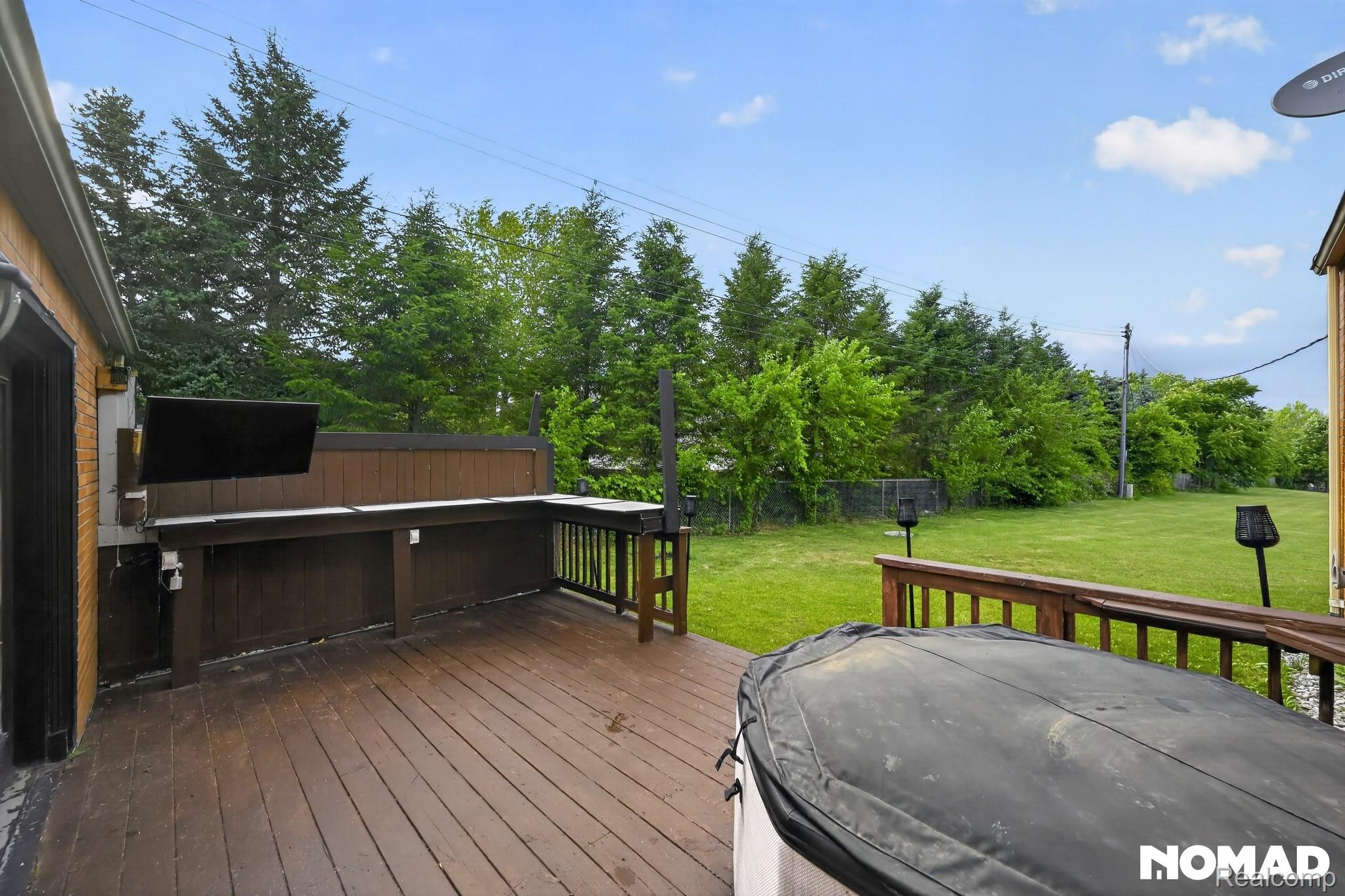 8315 Hilton Road Brighton, MI 48114 - Photo 6 of 26 Expansive wood deck with a built-in countertop and entertainment console, featuring a wood privacy screen and wood railings