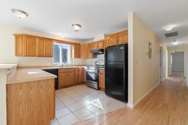 a kitchen with a refrigerator a sink and dishwasher with wooden cabinet
