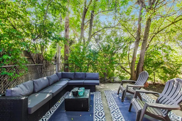 a view of a patio with couches a table and chairs with wooden fence and plants