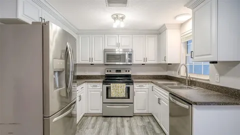 a kitchen with a refrigerator sink and cabinets