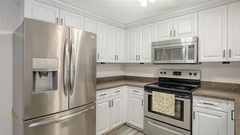 a kitchen with stainless steel appliances white cabinets white stove a refrigerator and a microwave