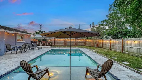 a view of a backyard with swimming pool and sitting area