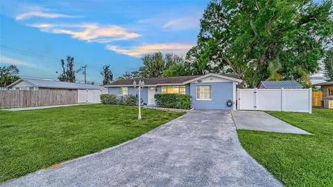 a view of a house with a yard and a large tree