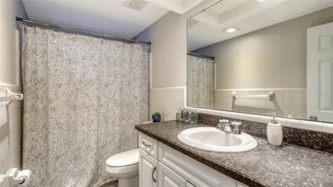 a bathroom with a granite countertop sink a toilet and a mirror