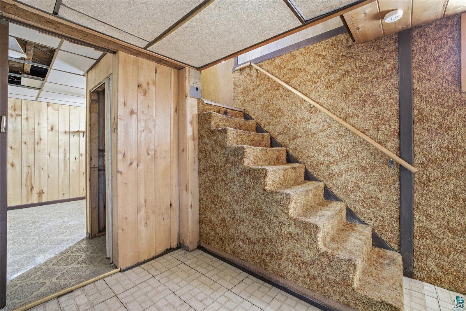709 Michigan Street Hibbing, MN 55746 - Photo 18 of 47 Staircase with wooden walls and brick patterned flooring