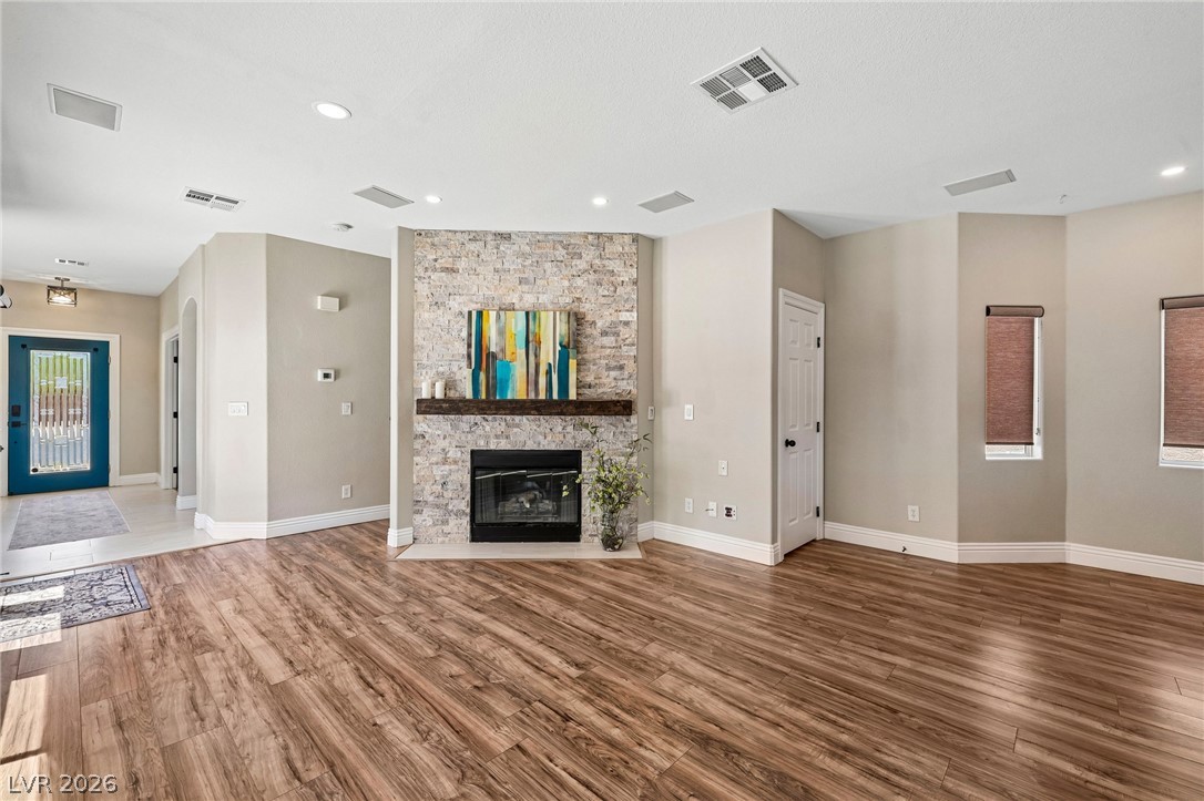 1176 Butternut Ranch Court Henderson, NV 89052 - Photo 5 of 60 A striking stone fireplace hearth anchors this grand living area with abundant natural illumination and rich wood flooring.