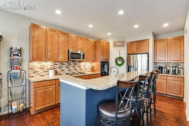 13873 Windy Oaks Road Colorado Springs, CO 80921 - Photo 11 of 28 a kitchen with stainless steel appliances granite countertop a stove top oven a sink a dining table and chairs