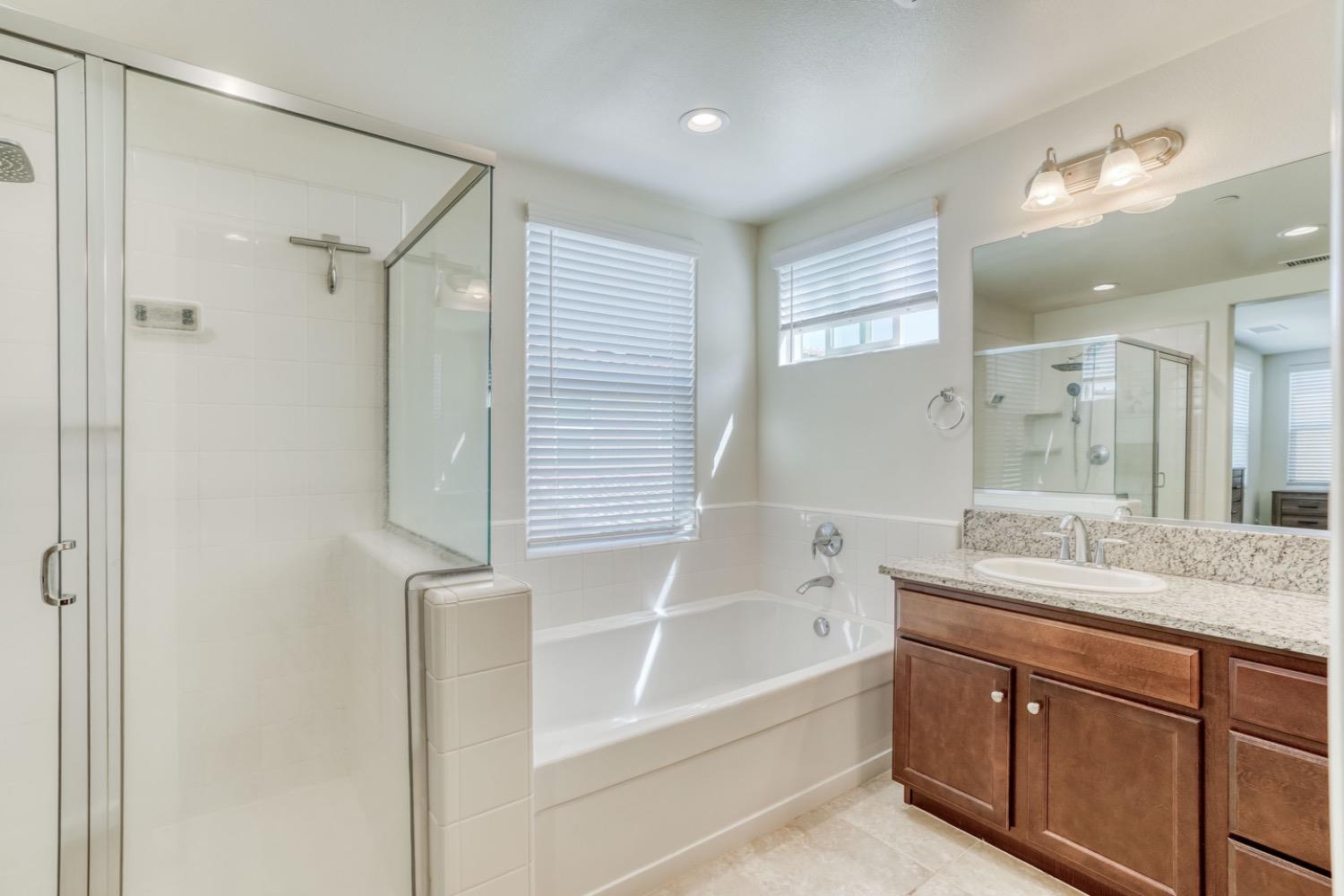 933 Winchell Way West Madera, CA 93636 - Photo 11 of 29 a bathroom with a granite countertop sink mirror bathtub and shower