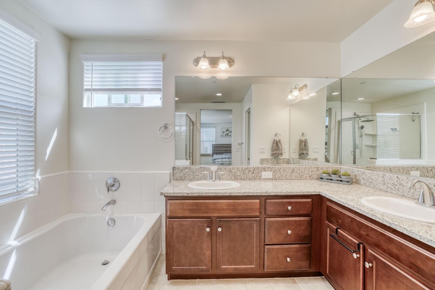 933 Winchell Way West Madera, CA 93636 - Photo 11 of 29 a bathroom with a sink double vanity granite tub and a mirror