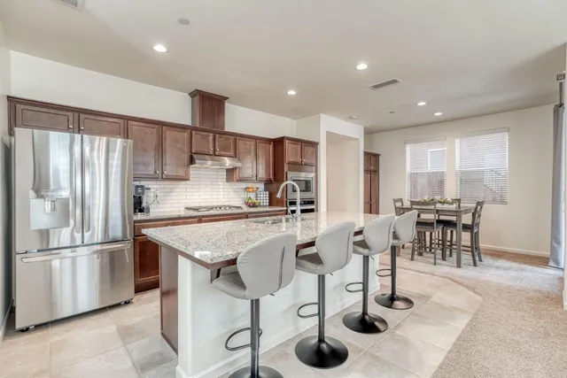 a kitchen with stainless steel appliances granite countertop a refrigerator and a stove top oven with white countertops