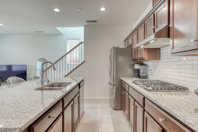 a kitchen with stainless steel appliances granite countertop a sink stove and refrigerator
