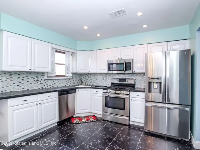 a kitchen with granite countertop a sink stainless steel appliances and cabinets