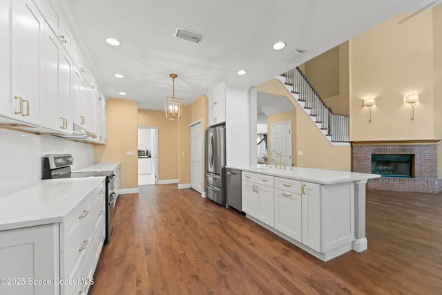 a view of an empty room with wooden floor fireplace and a window
