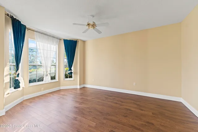 an empty room with chandelier fan and windows