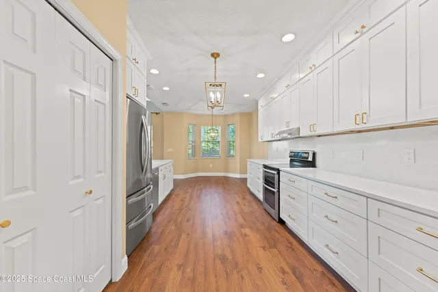 an empty room with wooden floor fireplace and windows