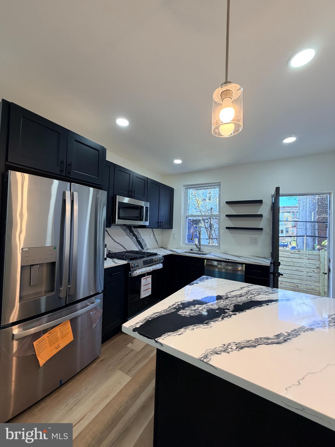 5436 Ridgewood Street Philadelphia, PA 19143 - Photo 5 of 30 a kitchen with stainless steel appliances kitchen island granite countertop a refrigerator a stove and a sink with wooden floor