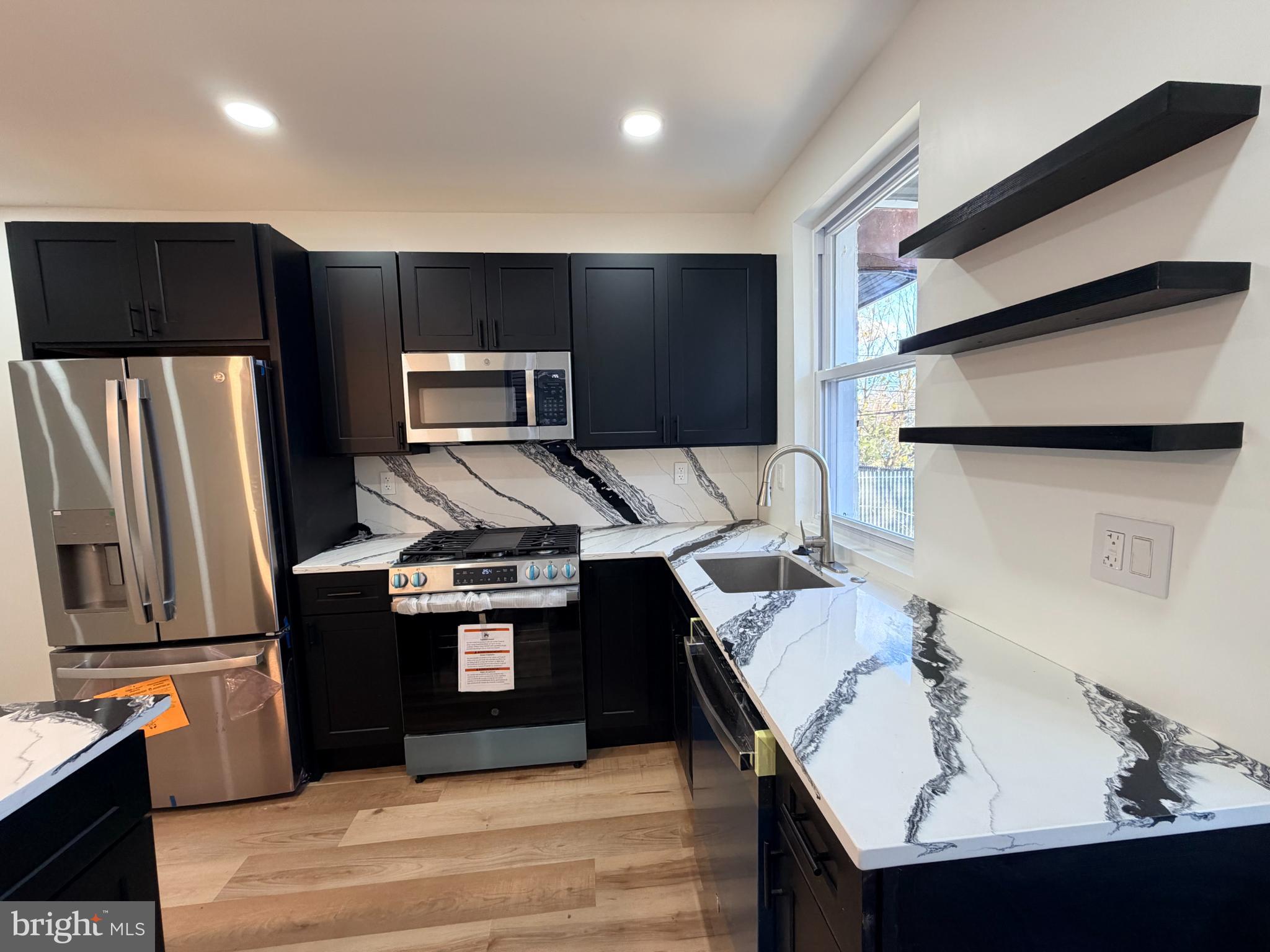 5436 Ridgewood Street Philadelphia, PA 19143 - Photo 8 of 30 a kitchen with stainless steel appliances granite countertop a sink stove and refrigerator