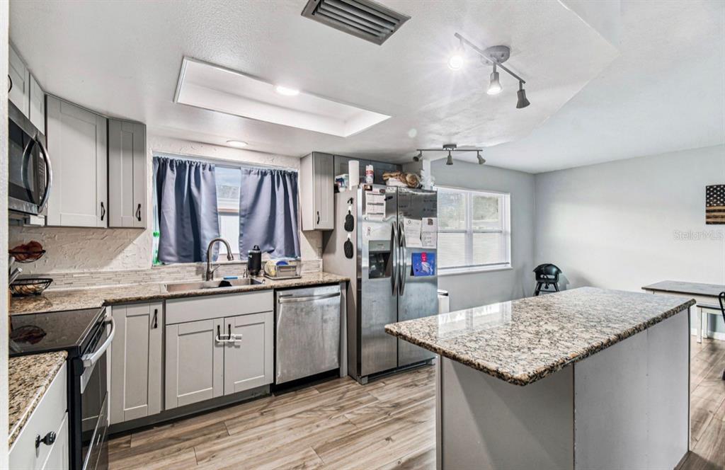 7112 Vista Way New Port Richey, FL 34653 - Photo 19 of 54 a kitchen with granite countertop cabinets sink and stainless steel appliances