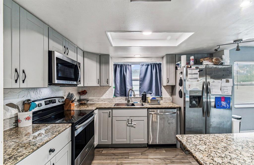 7112 Vista Way New Port Richey, FL 34653 - Photo 20 of 54 a kitchen with stainless steel appliances granite countertop a sink stove and refrigerator