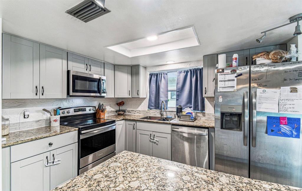 7112 Vista Way New Port Richey, FL 34653 - Photo 21 of 54 a kitchen with stainless steel appliances granite countertop a stove sink and cabinets