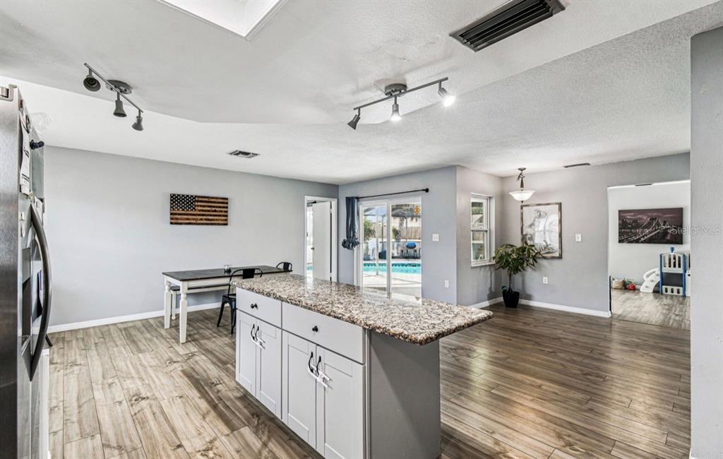 7112 Vista Way New Port Richey, FL 34653 - Photo 25 of 54 a open kitchen with granite countertop a stove and chairs