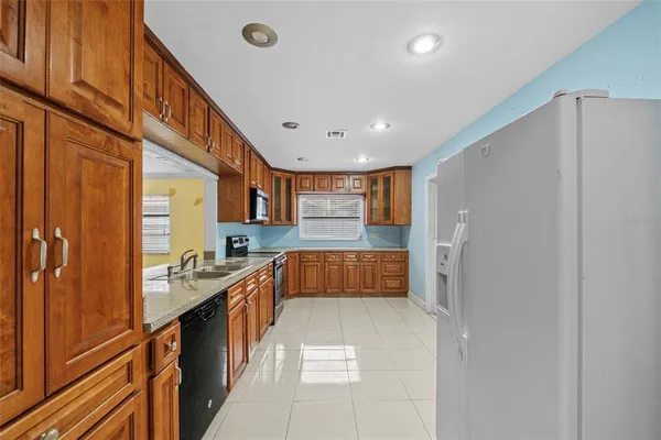 a kitchen with granite countertop wooden cabinets stainless steel appliances and a window