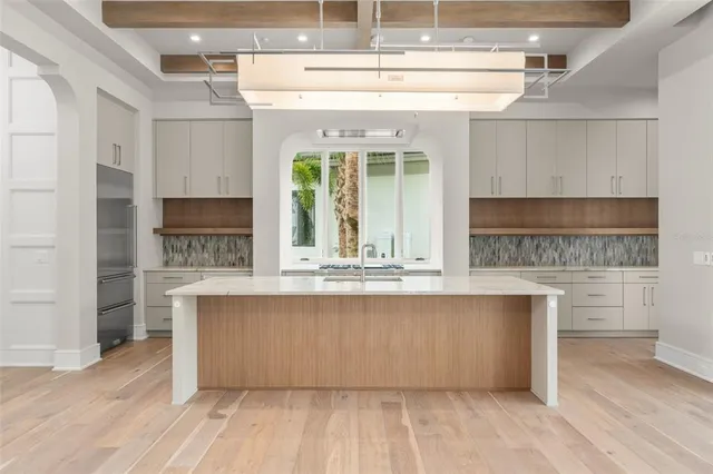 a large kitchen with kitchen island a sink wooden floor and stainless steel appliances