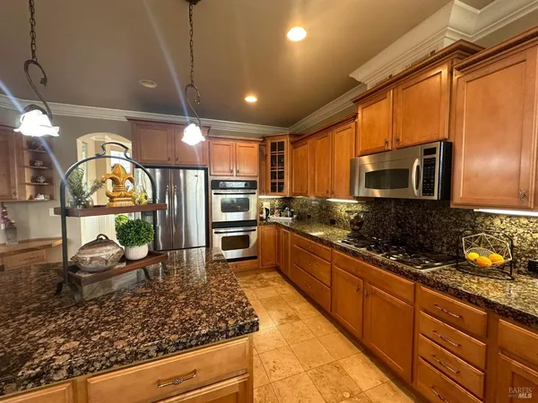 a kitchen with stainless steel appliances kitchen island granite countertop a stove refrigerator and cabinets
