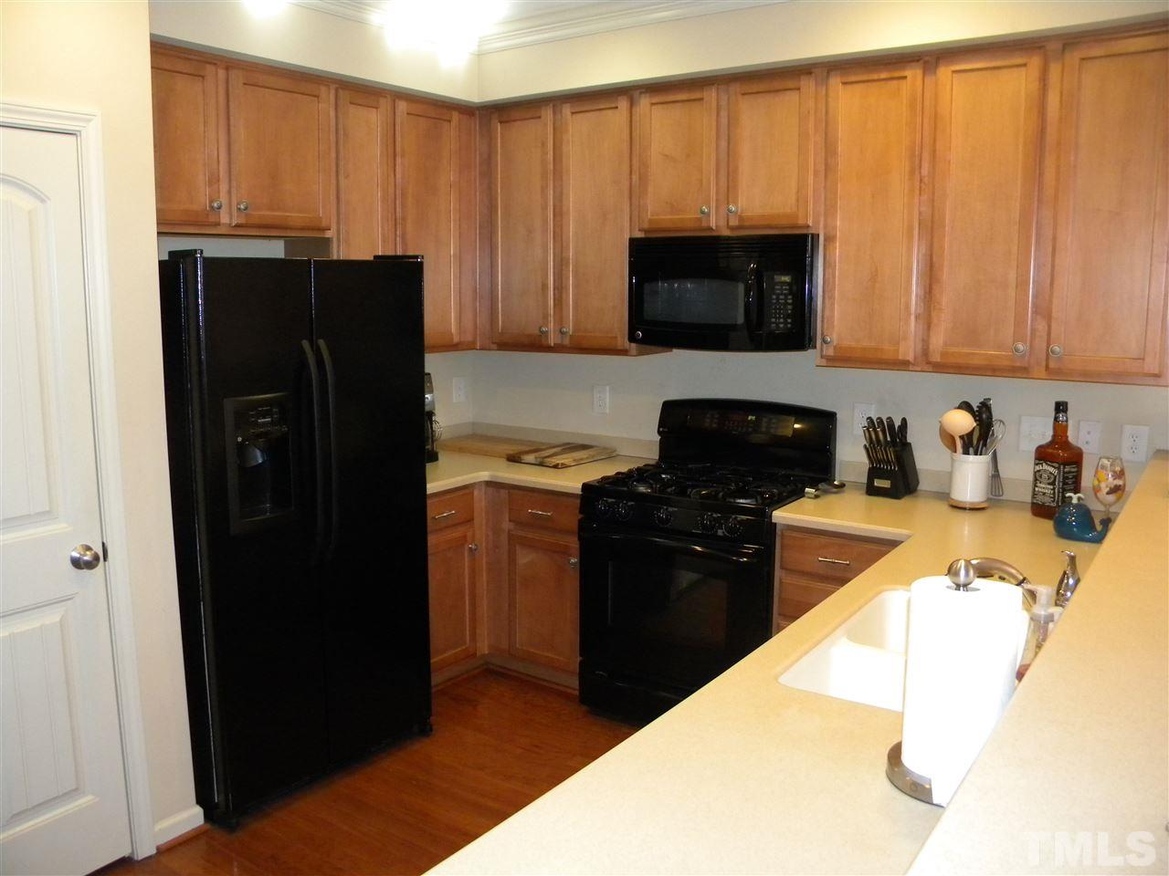 4608 Altha Street Raleigh, NC 27606 - Photo 5 of 12 a kitchen with granite countertop wooden cabinets and black appliances