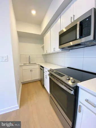 a kitchen with stainless steel appliances a stove a microwave and white cabinets