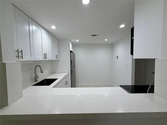 a kitchen with a sink a refrigerator and cabinets