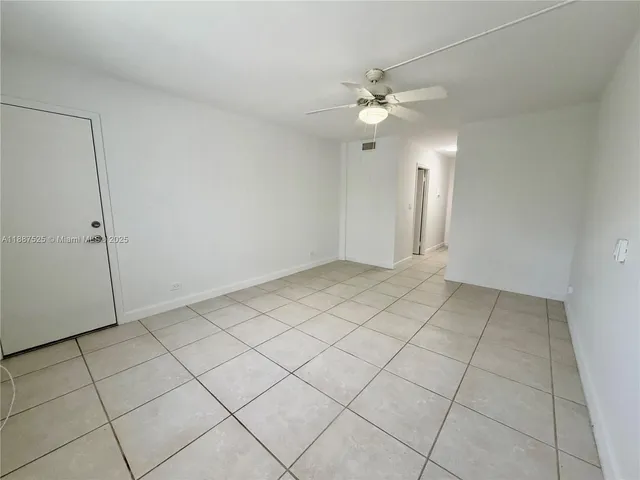 an empty room with white walls and fan