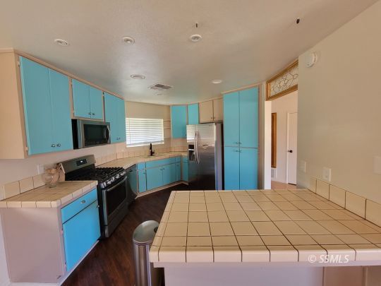 724 Ginger Avenue Ridgecrest, CA 93555 - Photo 7 of 21 a open kitchen with stainless steel appliances granite countertop a stove top oven a sink dishwasher and a refrigerator with wooden floor
