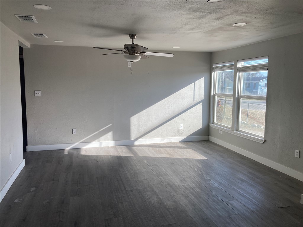 600 West St Marys Street Mathis, TX 78368 - Photo 2 of 11 an empty room with wooden floor fan and windows