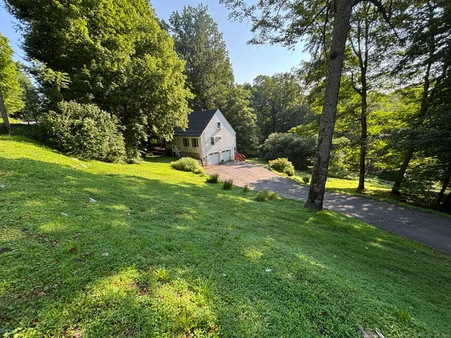 a house that is sitting in the grass with large trees