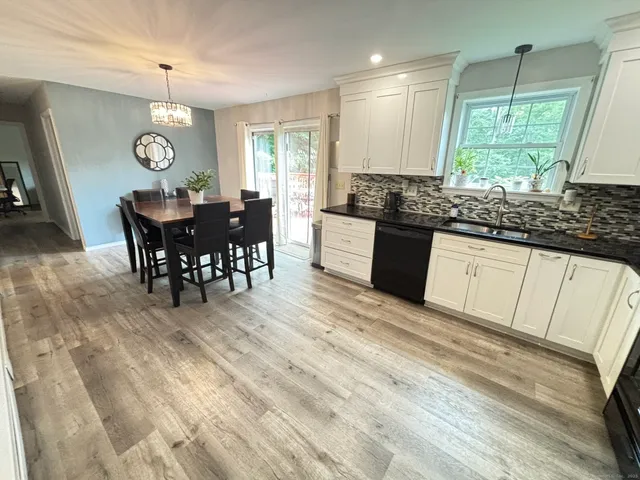 a large kitchen with granite countertop a stove a sink a dining table and chairs