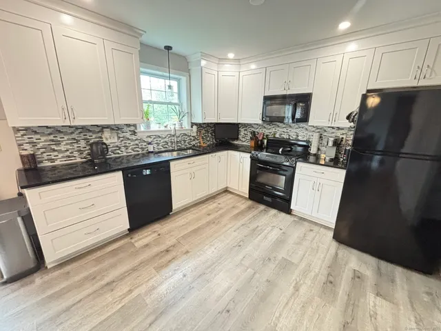 a kitchen with granite countertop a refrigerator stove top oven and sink