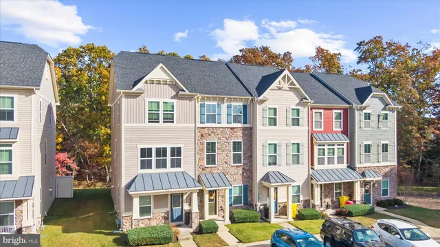a front view of a residential apartment building with a yard and potted plants