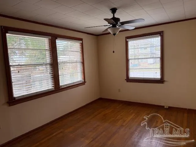 a view of an empty room with a window and wooden floor