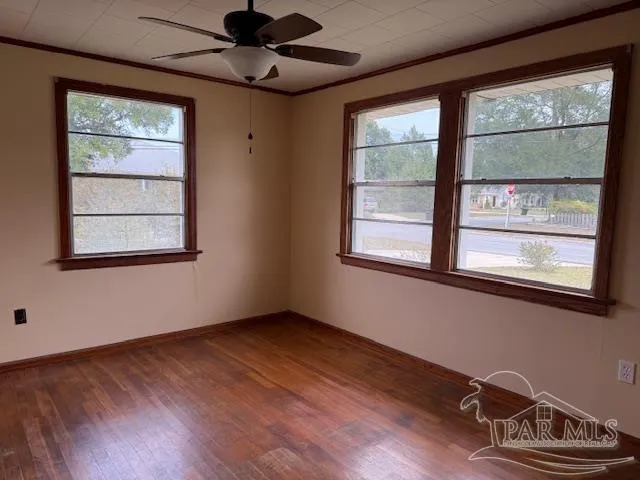 a view of an empty room with a window and wooden floor