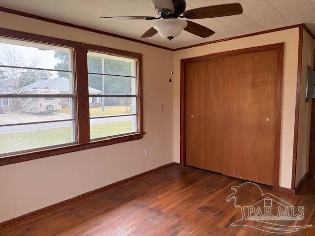 a view of an empty room with a window and wooden floor