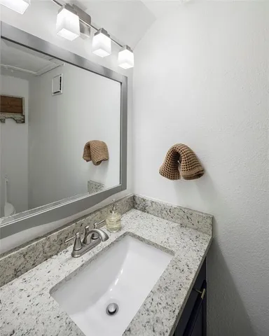 a bathroom with a granite countertop sink and a mirror