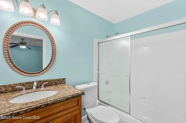 an empty room with wooden floor chandelier fan and windows