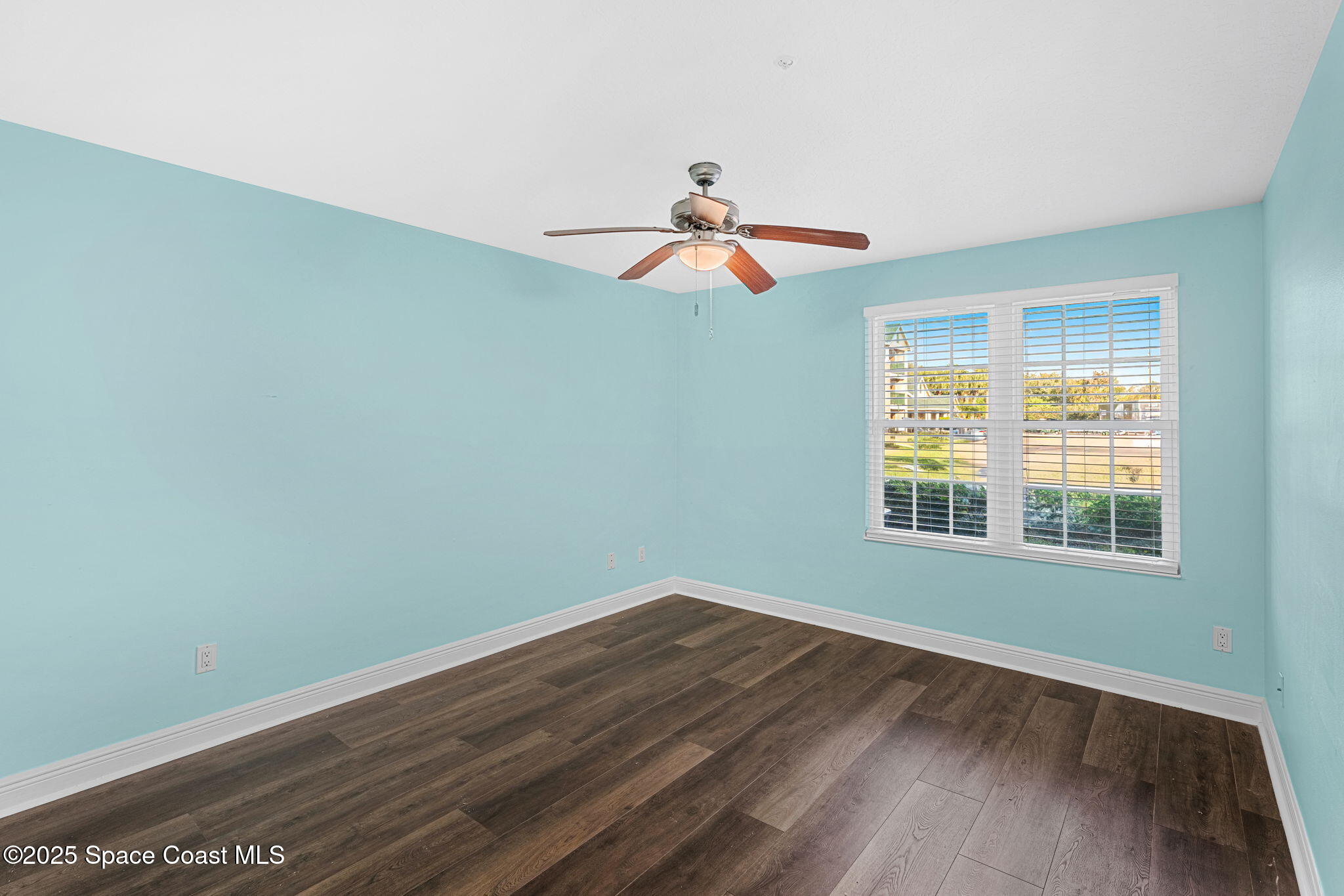 7667 North Wickham Road, Unit 103 Melbourne, FL 32940 - Photo 20 of 39 an empty room with wooden floor chandelier fan and windows